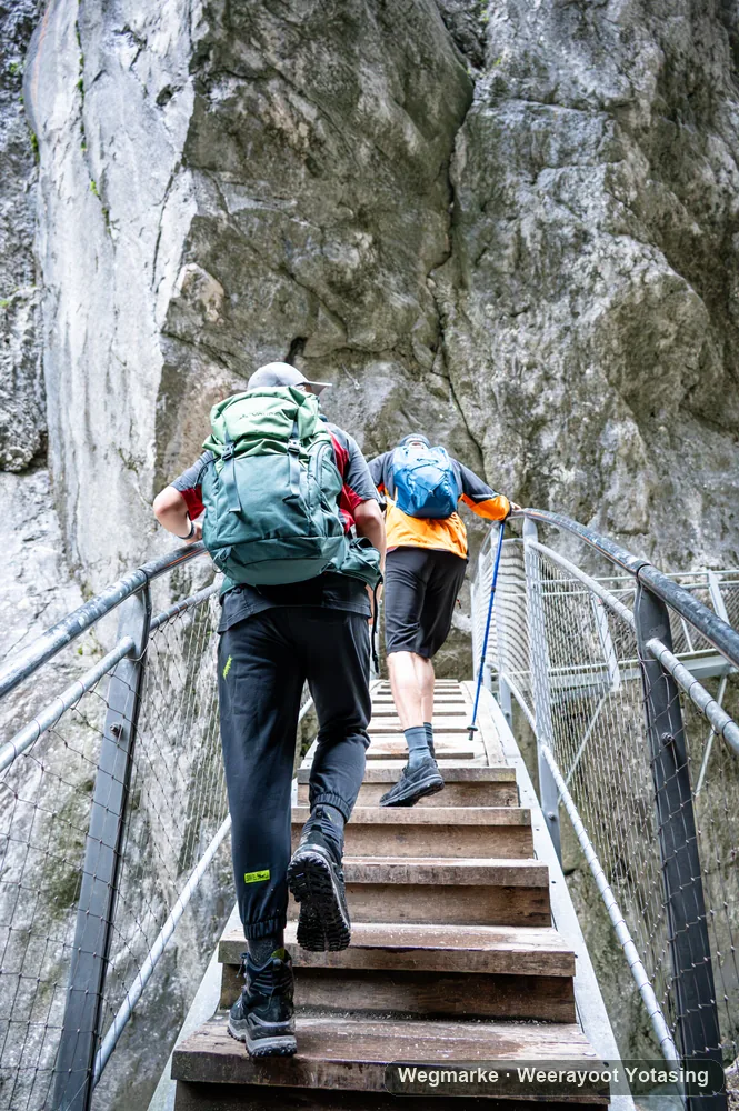 Hikers climbing metal steps between rock walls