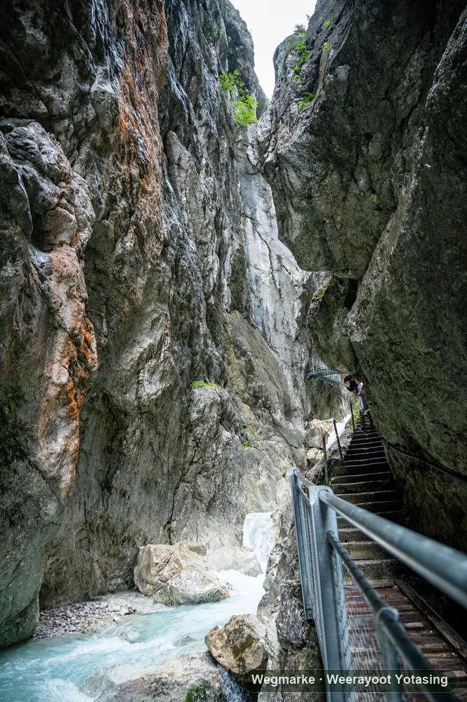 A narrow mountain gorge with stairs beside rushing water