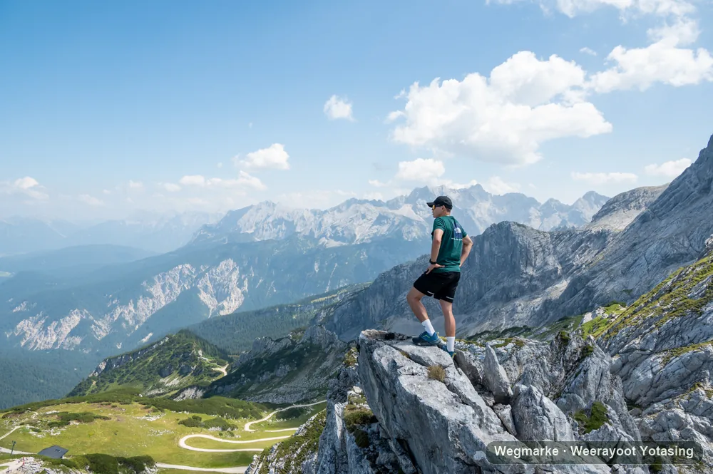 A hiker high above a green alpine basin