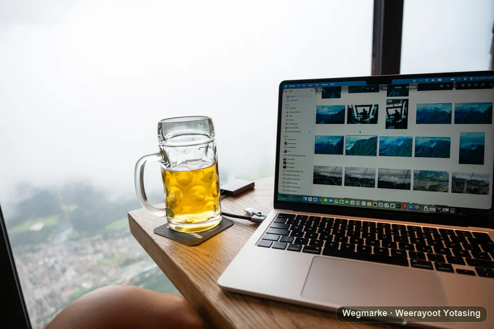 A laptop and drink beside a misty mountain window